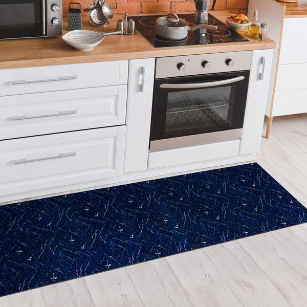 Blauer Teppichläufer mit abstraktem Muster in einer Küche vor weißen Küchenschränken.