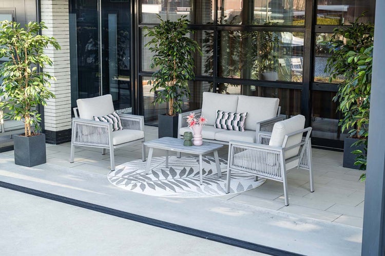Moderne Gartenlounge aus grauem Metall mit Seilbespannung, bestehend aus Sofa, zwei Sesseln und Couchtisch auf einer hellen Terrasse.