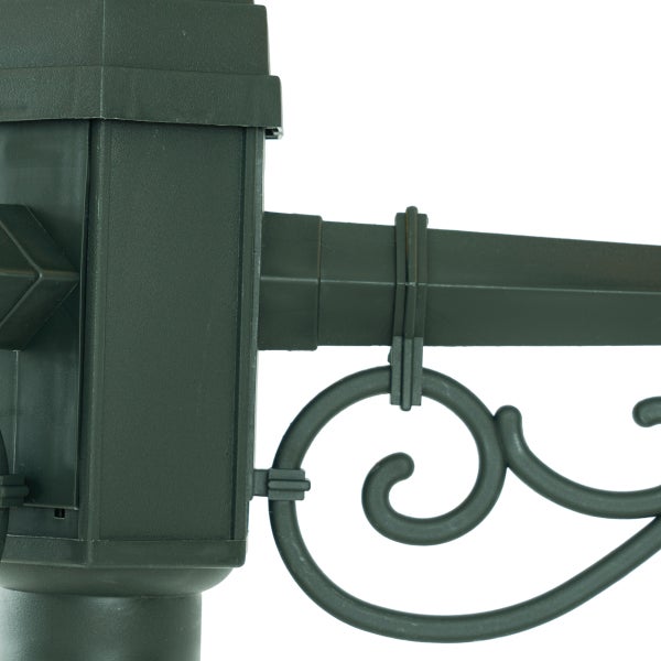 Detail einer dunkelgrünen Außenleuchtenhalterung aus Kunststoff mit dekorativem Schnörkel an einem quadratischen Pfosten.