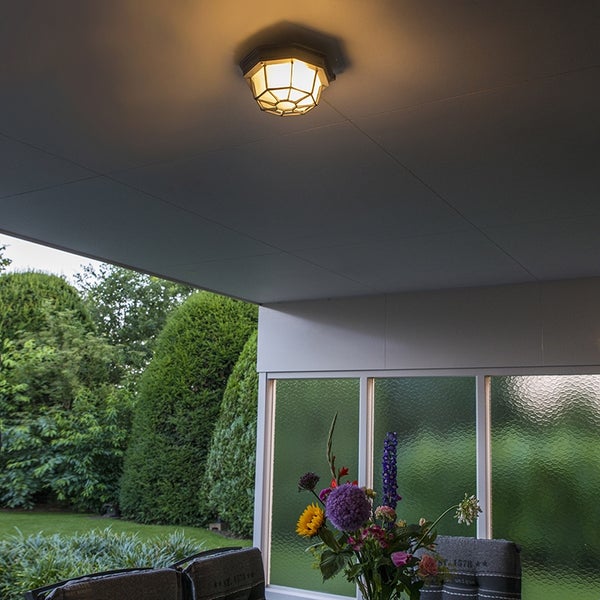 Außen-Deckenleuchte mit Gitterdesign an einer Terrassendecke, beleuchtet einen Gartenbereich mit Blumen und Hecken.