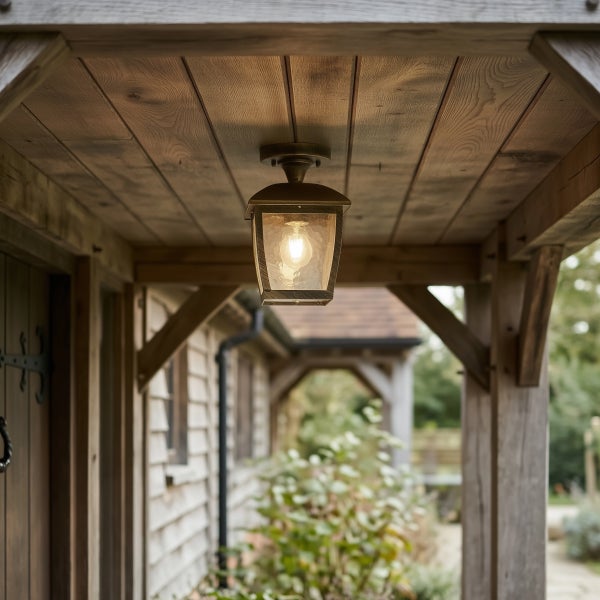 Eine rustikale Außenleuchte im Laternenstil, montiert unter einem hölzernen Vordach eines Hauses.