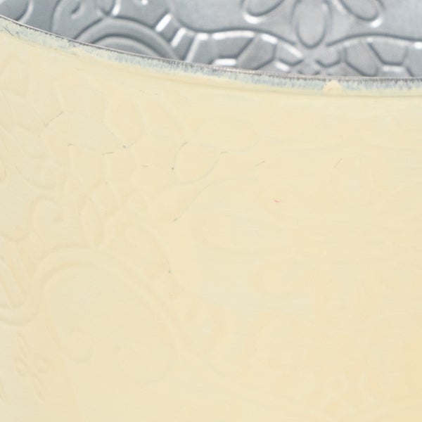 Detailansicht eines cremefarbenen Metall-Pflanztopfs mit geprägtem Blumenmuster.