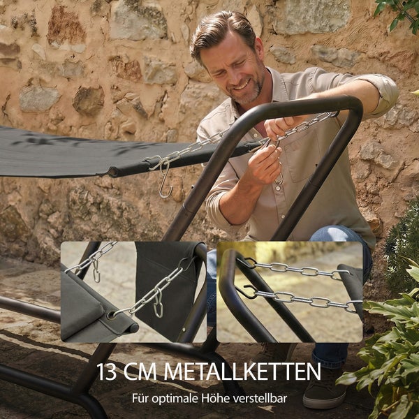 Ein Mann verstellt die Höhe einer Liege mit 13 Zentimeter langen Metallketten an einem schwarzen Gestell vor einer Steinmauer.