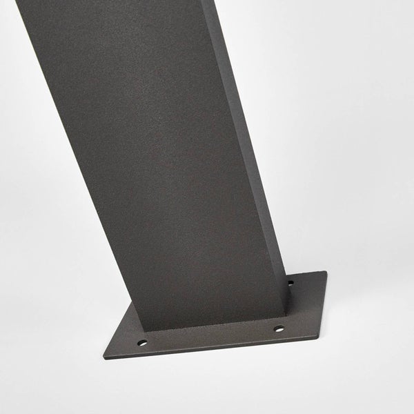 Nahaufnahme eines quadratischen Metallpfostens mit Bodenplatte und vier Befestigungslöchern, dunkel strukturiert.