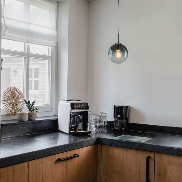 Küchenecke mit Kaffeemaschine, Gläsern und Pendelleuchte