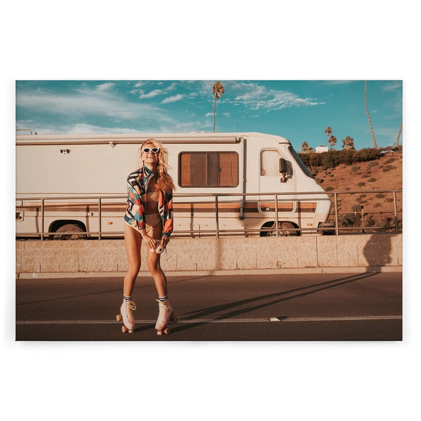 Wandbild mit einer Frau auf Rollschuhen vor einem Wohnmobil in einer sonnigen Küstenlandschaft
