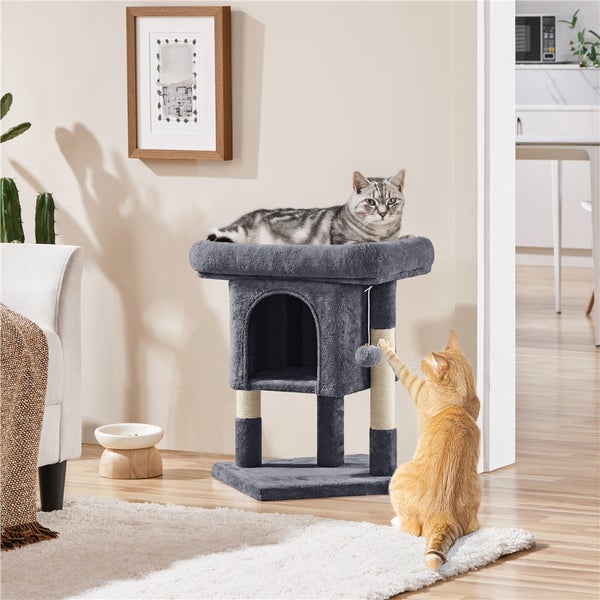 Katzenkratzbaum mit Höhle und zwei Katzen in einem hellen Raum.