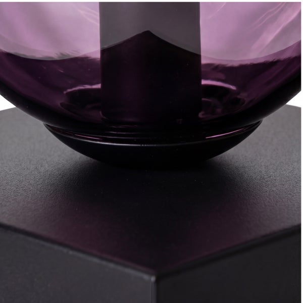 Detailansicht einer Leuchte mit schwarzem strukturiertem Fuß und lila transparentem Glaselement.