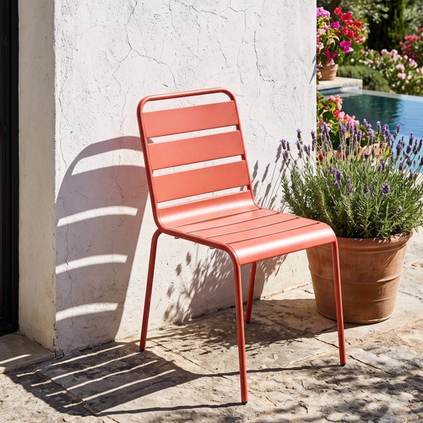 Moderner Gartenstuhl aus Metall mit Querstreben auf einer sonnigen Terrasse neben einem Tontopf mit Lavendel und einem Pool im Hintergrund.