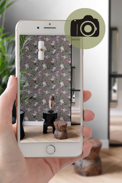 Ansicht eines Smartphones, das ein Foto von einem Raum mit Blumentapete, Beleuchtung und Dekorationsartikeln anzeigt