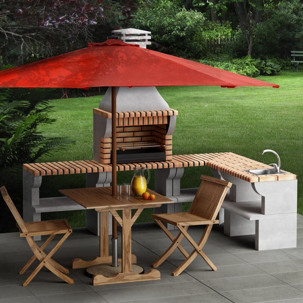 Gartenküche aus Stein mit gemauertem Grill und Spülbecken sowie Gartentisch mit zwei Holzstühlen und Sonnenschirm auf einer Terrasse.