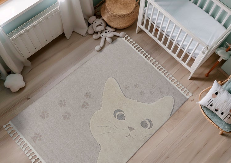 Kinderzimmerteppich mit Katzenmotiv und Pfotenabdrücken sowie Fransen in einem gemütlich eingerichteten Babyzimmer.