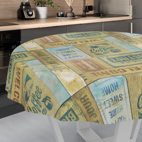 Runde Tischdecke in Holzoptik mit Vintage-Schriftzügen wie Coffee und Bistro auf einem Tisch in einer hellen, modern eingerichteten Küche.