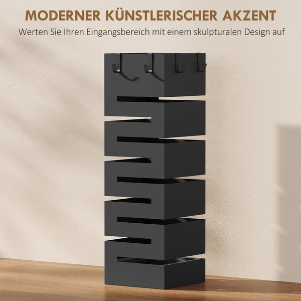 Moderner schwarzer Schirmständer im skulpturalen Zickzack-Design mit Haken, stehend auf Holzboden im Eingangsbereich.