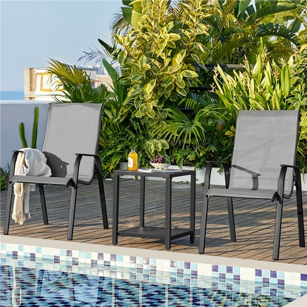 Zwei Gartenstühle mit grauem Textilbezug und ein schwarzer quadratischer Beistelltisch auf einer Holzterrasse am Pool.