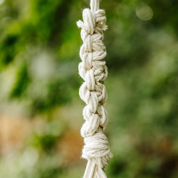 Nahaufnahme eines geflochtenen Baumwollseils mit dekorativen Knoten in Naturweiß für Makramee oder Hängesessel.