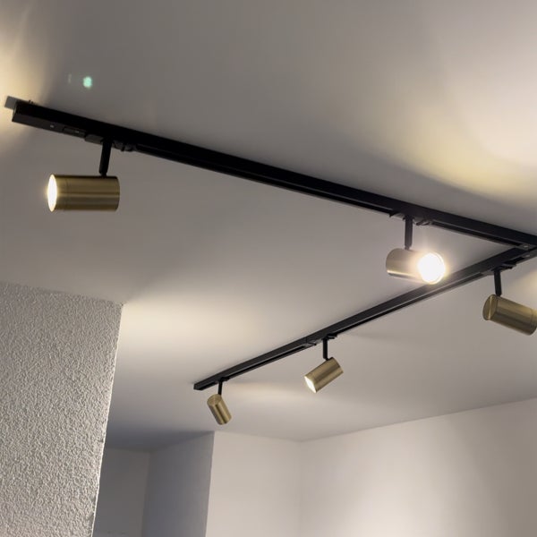 Schwarzes Schienensystem mit fünf verstellbaren LED Strahlern in Metalloptik an einer Decke montiert
