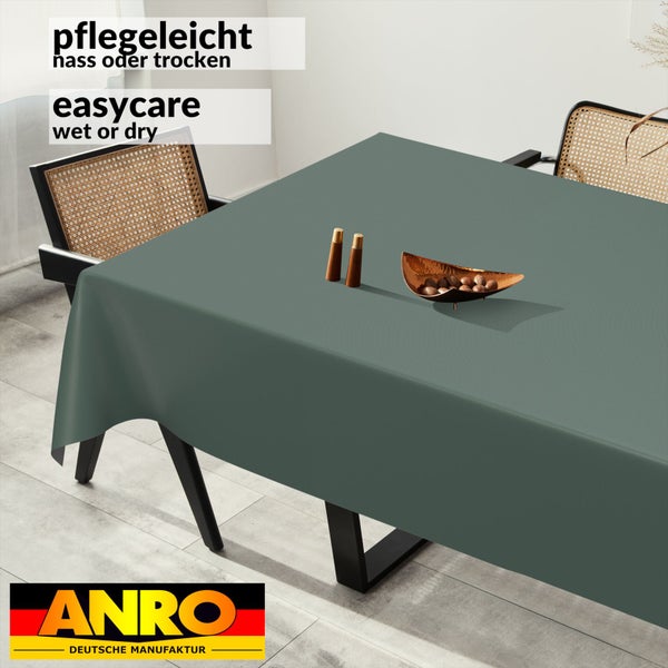 Pflegeleichte rechteckige Tischdecke auf einem Esstisch mit Rattanstühlen und Dekoration. ANRO Logo.