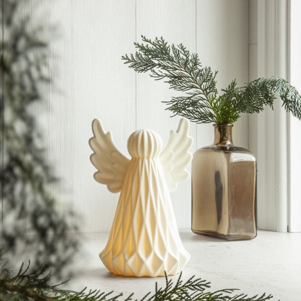 Dekorative Engel Figur neben einer Glasvase mit Tannenzweigen