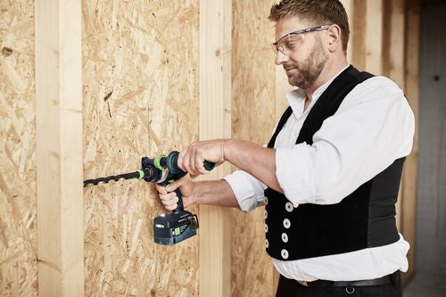Handwerker bohrt mit einer Bohrmaschine ein Loch in eine Holzwand