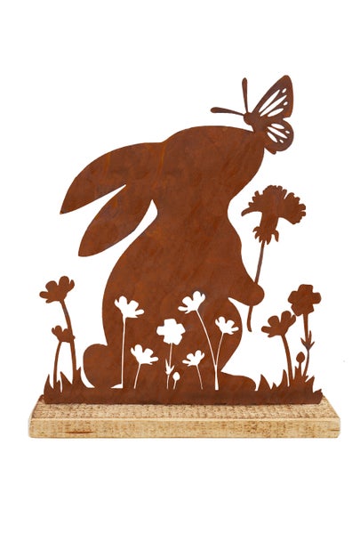 Osterdekoration Hase mit Blume und Schmetterling aus Edelrost auf einem Holzsockel stehend.