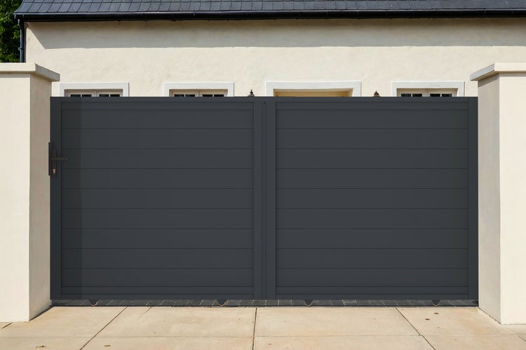 Modernes, zweiflügeliges Einfahrtstor aus anthrazitfarbenen horizontalen Lamellen, montiert zwischen zwei Mauerpfeilern vor einem Wohnhaus.