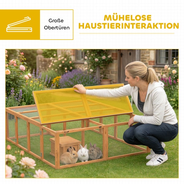 Frau öffnet die große obere Tür eines hölzernen Kleintierfreilaufs im Garten mit drei Kaninchen im Inneren.