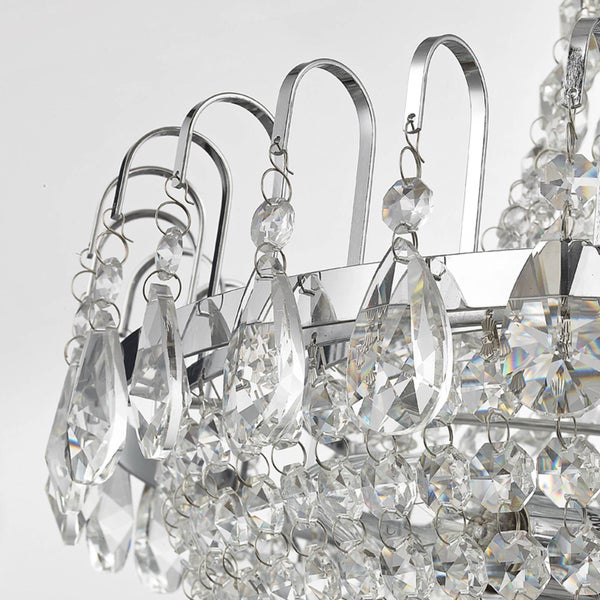 Detailansicht eines Kristallkronleuchters mit tropfenförmigen Anhängern aus Glas und Elementen aus verchromtem Metall.