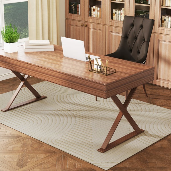 Klassischer Schreibtisch aus dunklem Holz mit X-förmigen Beinen, Lederstuhl und Laptop in einem hellen Arbeitszimmer mit Bücherregal.