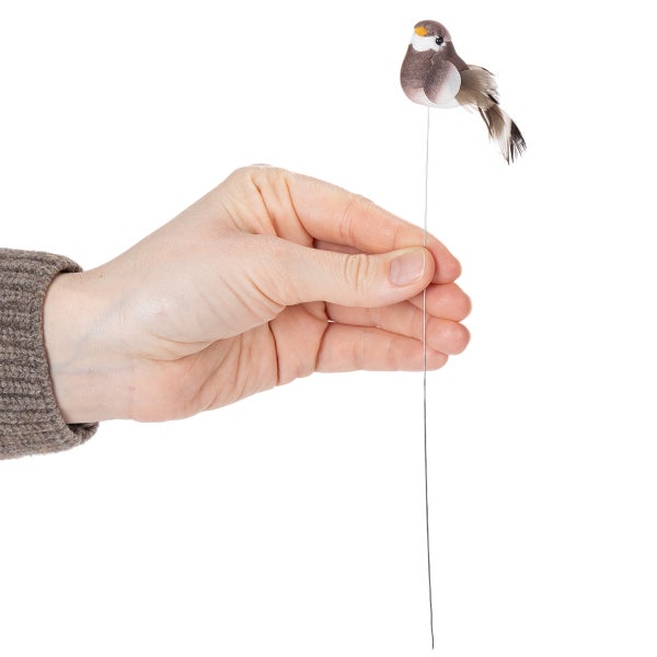 Dekorativer Vogel auf Draht in Hand gehalten