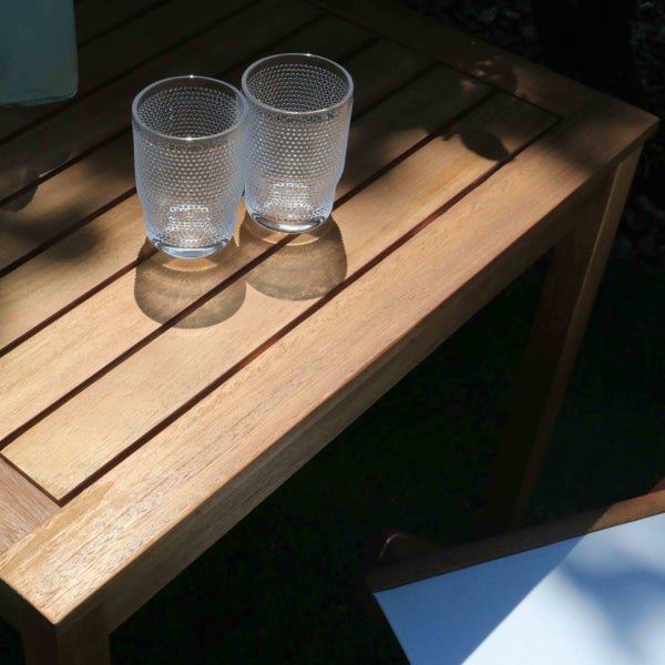 Zwei strukturierte Trinkgläser auf einem Gartentisch aus Holz mit Lattenstruktur im Sonnenlicht.