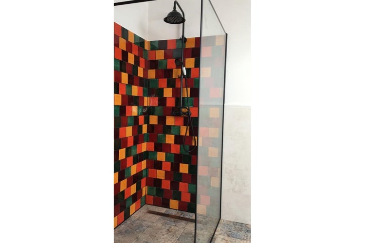 Duschkabine mit farbigen Fliesen und schwarzer Duscharmatur