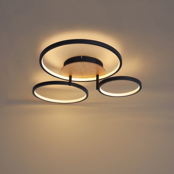 Moderne LED Deckenleuchte mit drei ringförmigen Elementen aus Metall und Holzdekor für eine wohnliche Atmosphäre.