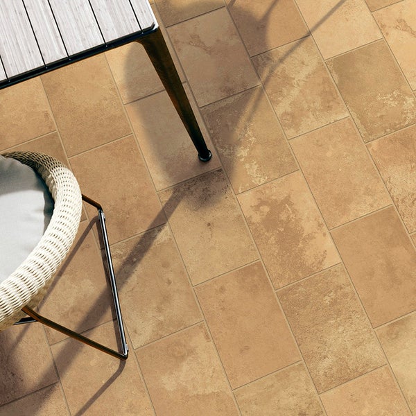 Terrasse mit rechteckigen Fliesen in Steinoptik, verlegt im Verband, mit Teil eines Gartentischs und eines Stuhls.
