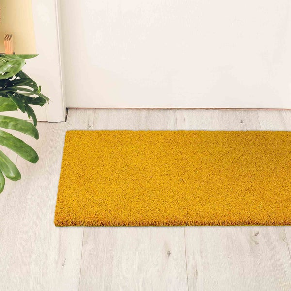 Fußmatte aus Kokosfaser vor einer Tür auf einem Holzboden