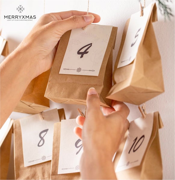 Adventskalender mit nummerierten Papiertüten und Händen