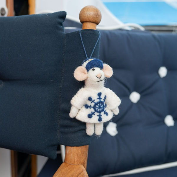 Dekoratives Schaf mit Mütze und Schneeflockenmuster hängt an einem Stuhl