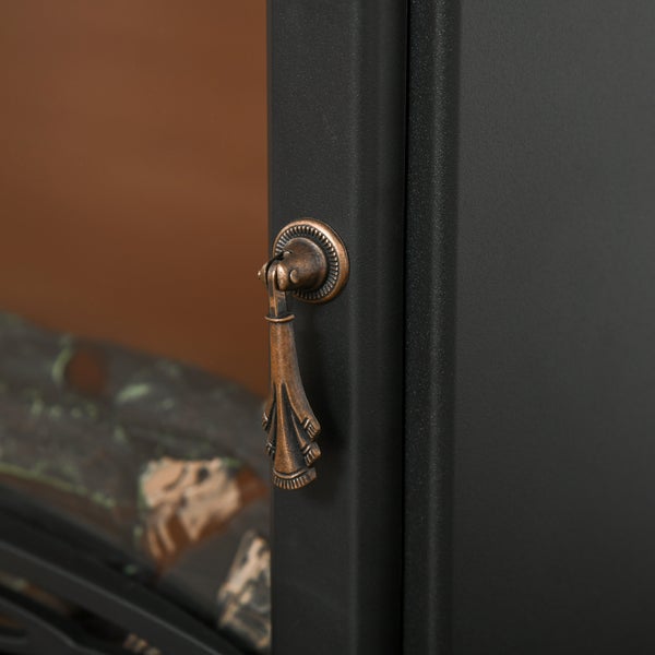 Detailaufnahme eines bronzefarbenen Metallgriffs an einem schwarzen Kamingehäuse im Vintage-Stil.