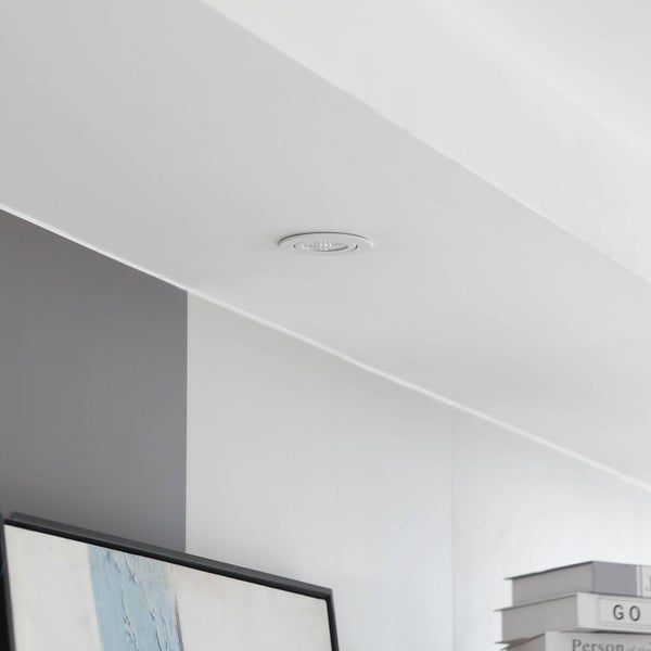 Runder LED Einbaustrahler montiert in einer weißen Zimmerdecke in einem hellen, modern gestalteten Wohnbereich.