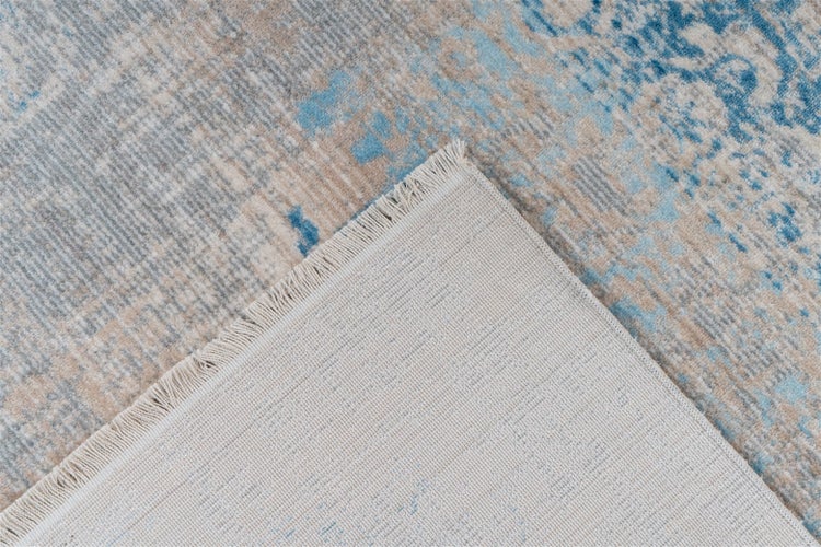 Teppich mit abstraktem Muster, umgeschlagene Ecke mit Fransen und strukturierter Rückseite.