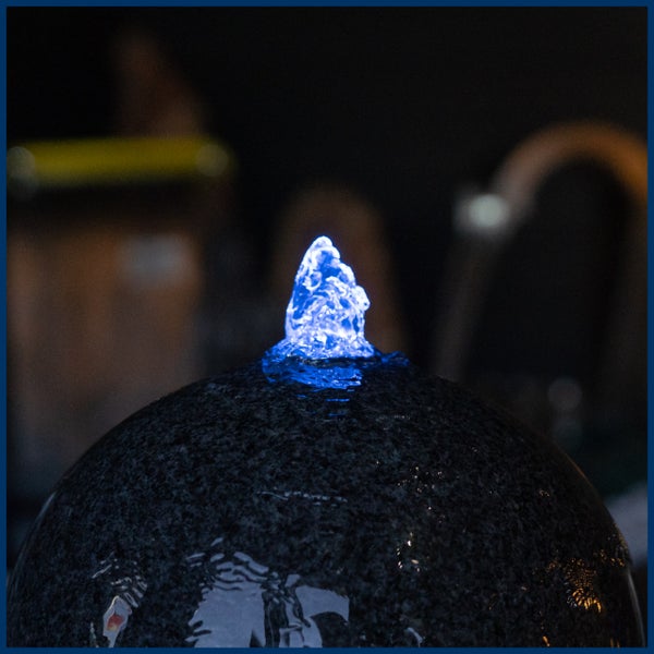 Granit-Kugelbrunnen mit blauer LED-Beleuchtung und sprudelndem Wasser.