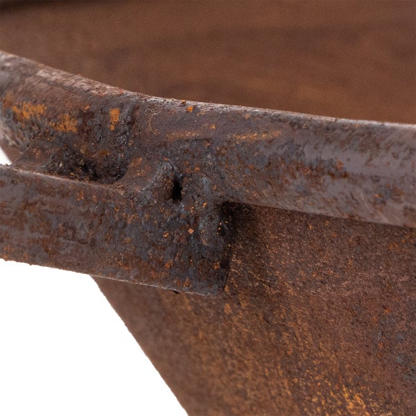 Detailaufnahme der Kante und des Griffs einer rostigen Feuerschale aus Metall.