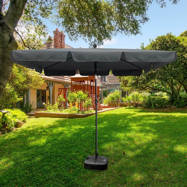 Rechteckiger Sonnenschirm mit Ständer auf Rasen vor einem Haus.
