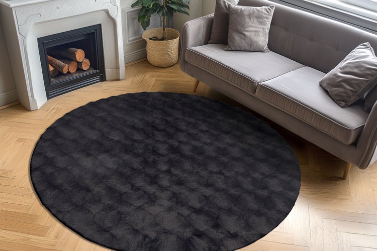 Runder Wohnzimmerteppich mit strukturierter Oberfläche in einem elegant eingerichteten Wohnbereich mit Kamin und Sofa auf Parkettboden.