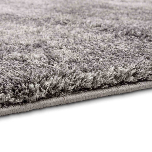 Nahaufnahme eines Hochflor-Teppichs mit weicher Textur und eingefasster Kante.