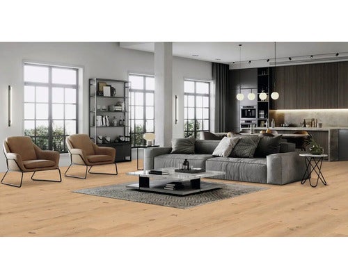 Wohnzimmer mit hellem Holzboden, Sofa, Sesseln und offener Küche.