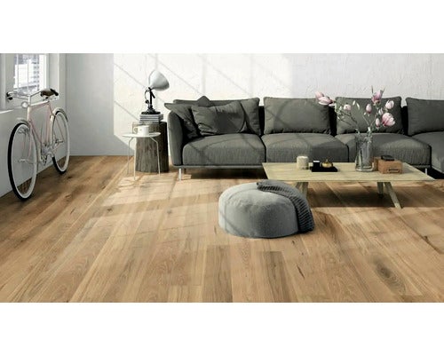 Wohnzimmer mit Holzboden, Sofa und Fahrrad am Fenster