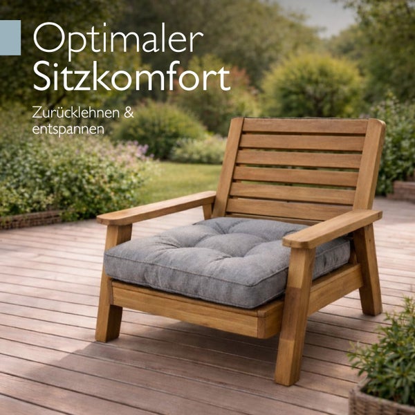 Ein hölzerner Gartenstuhl mit einem bequemen Sitzkissen steht auf einer Holzterrasse in einem grünen Garten.