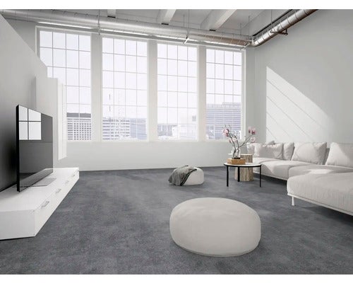 Modernes, helles Wohnzimmer mit dunklen Bodenfliesen in Betonoptik, weißem Sofa und großen Fenstern.
