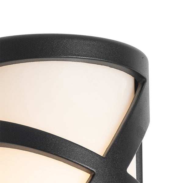 Detailaufnahme einer modernen Außenwandleuchte mit strukturiertem schwarzem Metallrahmen und weißem Diffusor in geschwungenem Design.